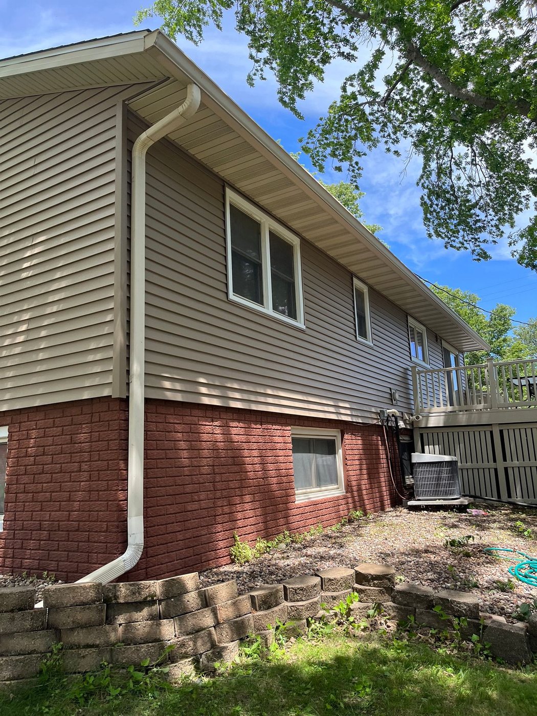 Walnut vinyl siding along the back of a raised-ranch home in Eldridge, Iowa, by Mitten