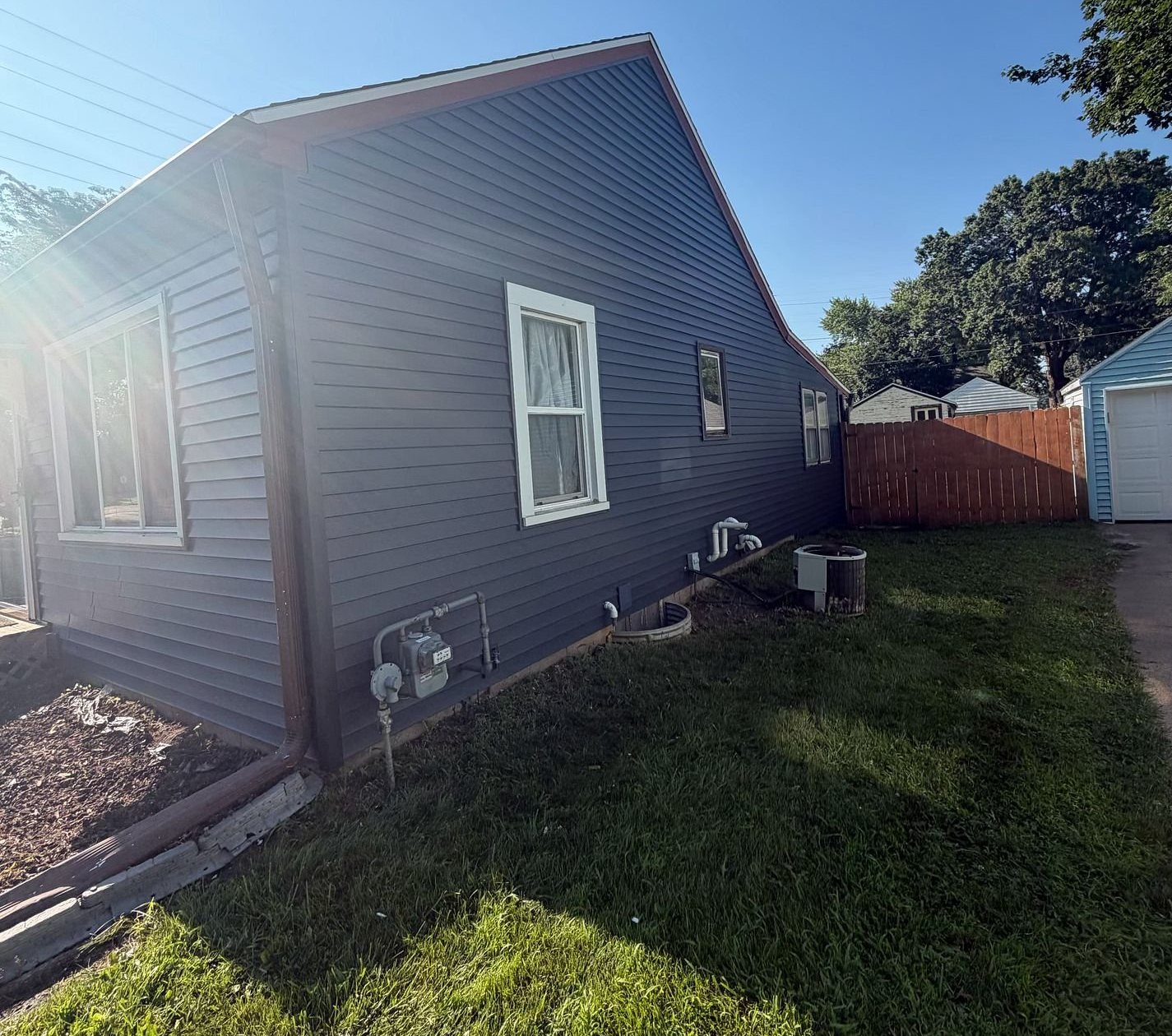 New navy blue Royal Estate vinyl siding with white window trim on the side of a Waterloo, Iowa home, by Mitten
