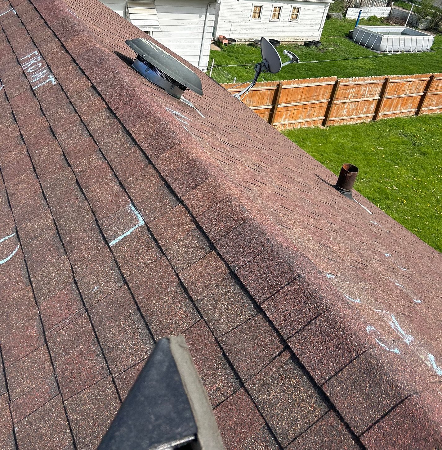 Old shingles on a Waterloo, Iowa roof with storm damage marked in chalk during a Mitten inspection